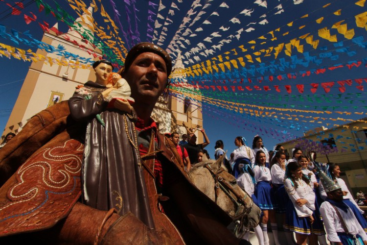 Homens carregando o tronco do Pau da Bandeira durante a celebração em Barbalha, Ceará
