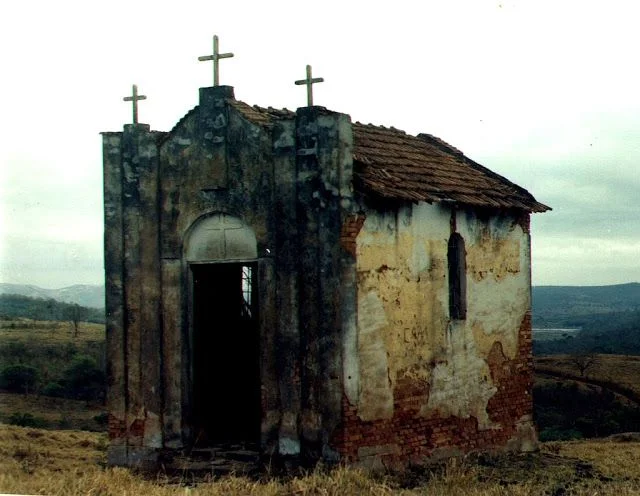 Ruínas de uma igreja antiga, cercada por árvores, evocando histórias e lendas locais