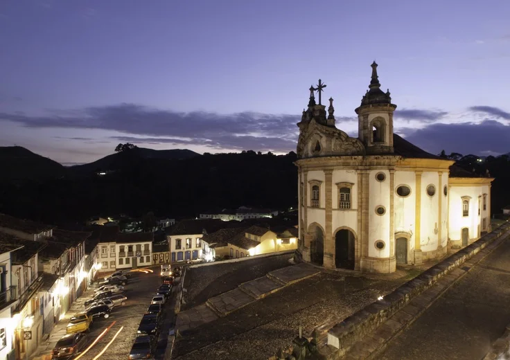 Vista aérea de Ouro Preto mostrando casarios coloniais e igrejas históricas em meio às montanhas.
